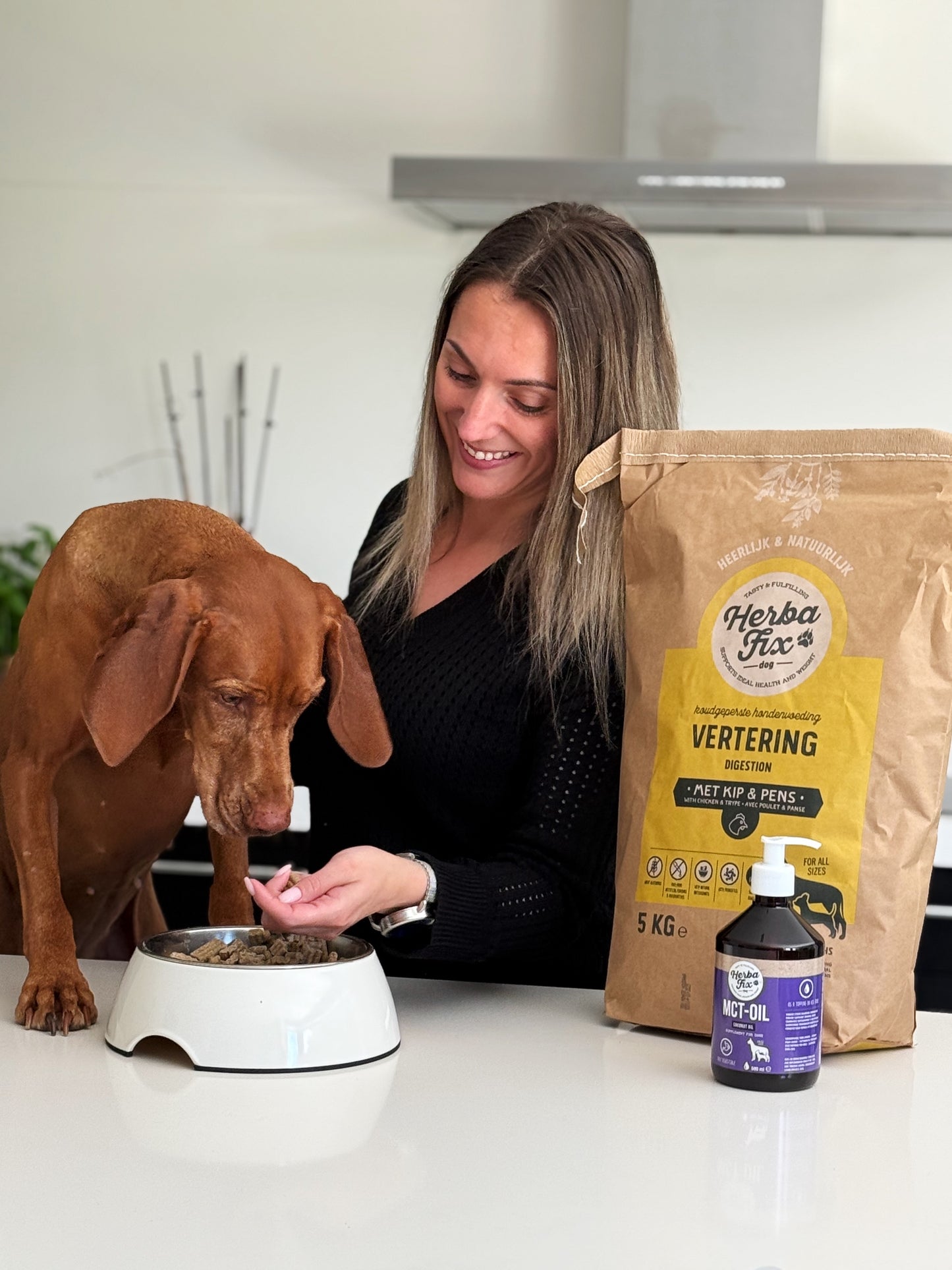 Hond proeft in de keuken van Herbafix Vertering brokjes samen met eigenaresse